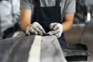 Técnico aplicando graxa lubrificante em peça mecânica para proteger e garantir o bom funcionamento de rolamentos automotivos.