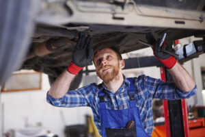 Mecânico realizando inspeção e montagem do semieixo automotivo em veículo suspenso no elevador, durante manutenção do conjunto traseiro.