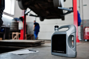Galão de óleo sintético de motor em ambiente de oficina, simbolizando a importância da troca regular de fluídos para a manutenção do carro.